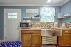 A kitchen with a microwave, sink, and a window with a view of trees. - On-site Trails & Wildlife! Hill Country Escape (Utopia)