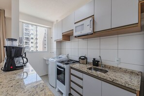 A modern kitchen with a gas stove, a microwave, a kettle, and a coffee maker. - Mirante #902 - Balcony With Sea View By Carpediem (Fortaleza)