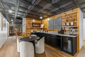 Eine moderne Küche mit einer zentralen Kochinsel, schwarzen Schränken und einer Wand in Holzoptik.
