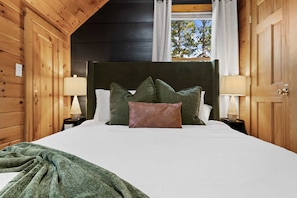 Ein Schlafzimmer mit einem Holzkopfteil, weißer Bettwäsche und zwei Nachttischlampen.