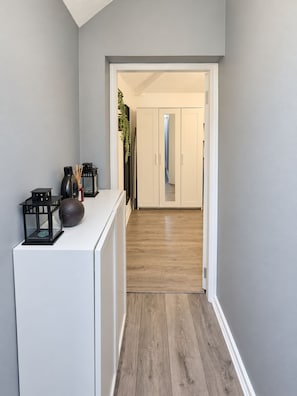 A hallway with a white console table, black lanterns, and a plant. - Large 1-bed Apartment in Manchester City Center (Manchester)