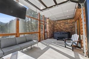 A modern outdoor living area with a stone fireplace, a sofa, and a chair. - Er61 Smoky Mountain Swim-inn 2 Bedroom Cabin (Pigeon Forge)