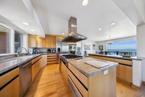 Eine moderne Küche mit Holzausstattung, Edelstahlgeräten und einer großen Kochinsel mit Granitplatte.