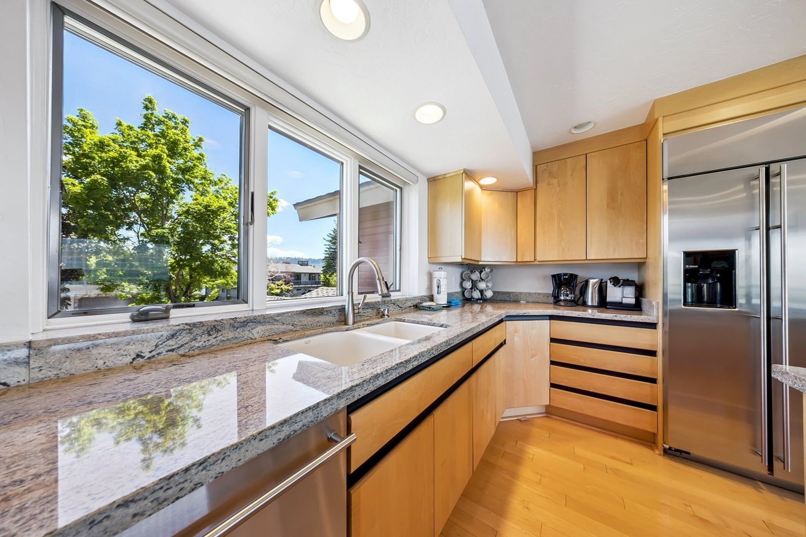 A modern kitchen with a granite countertop, stainless steel appliances, and wooden cabinets.