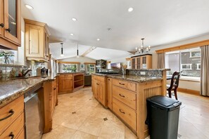 A spacious kitchen with wooden cabinets, granite countertops, and a large island. - 615 Alpine Drive 3 Bedroom Home (South Lake Tahoe)