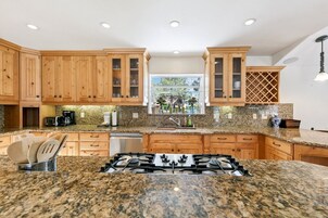 Una cocina con encimeras de granito, armarios de madera, estufa a gas y ventana con vistas.