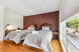 Habitación de hotel con dos camas, un escritorio, una lámpara y una ventana con vistas al exterior.
