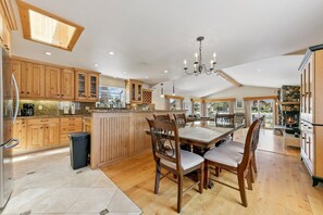 A spacious kitchen with wooden cabinets, a central island, and a dining area with a chandelier. - 615 Alpine Drive 3 Bedroom Home (South Lake Tahoe)