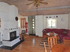 Un salon avec une cheminée, un plafond en bois, un canapé rouge et une table à manger.