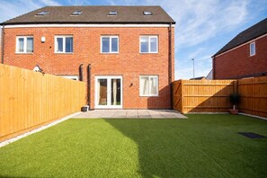 A two-story brick house with a fenced backyard, a sliding glass door, and a small garden. - House Sleeps 7 With Garden (Wolverhampton)