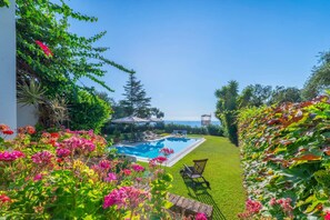 A swimming pool surrounded by lush greenery and a clear view of the ocean. - Villa Grand Barbati Beach by Villa Plus (Mparmpati)