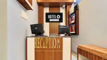 Ein Empfangsschalter mit einem Schild, auf dem 'HOTEL OYO-Serviced' steht, und zwei Monitore.