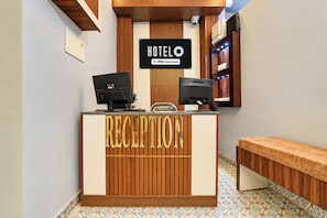 Un mostrador de recepción con un letrero que dice 'HOTEL OYO-Serviced' y dos monitores.