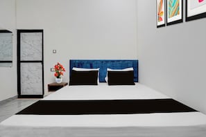 Una camera da letto moderna con un letto grande, una testiera blu e un comodino con un vaso di fiori.