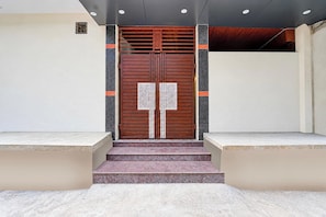 Une entrée moderne avec une porte double, des marches menant à l’entrée, et un design simple et épuré.