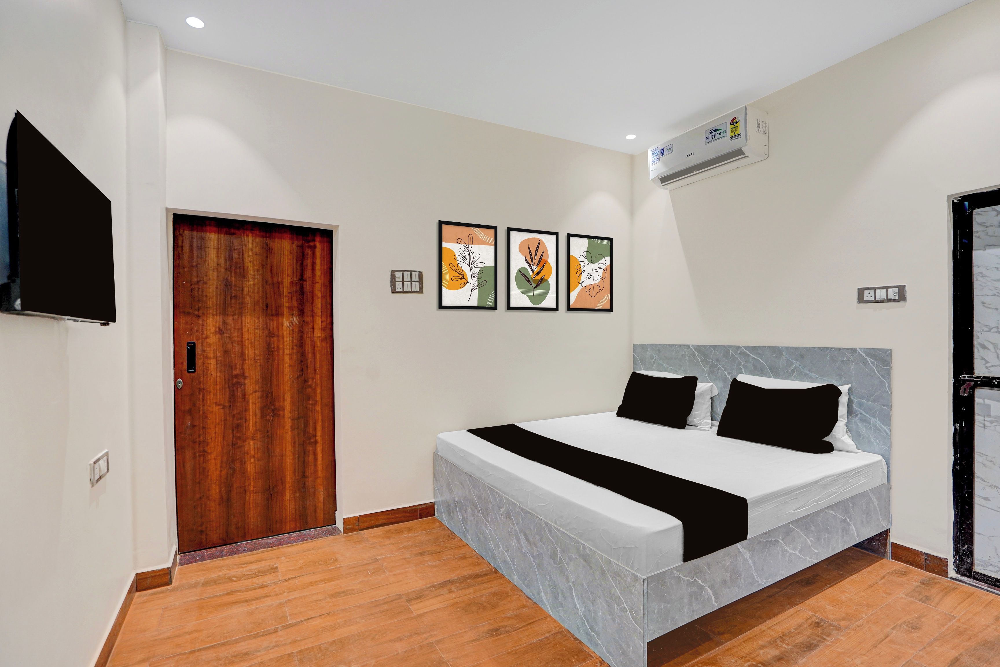 Habitación de hotel con cama, televisor de pantalla plana, puerta de madera y una obra de arte en la pared.