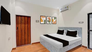 Habitación de hotel con cama, televisor de pantalla plana, puerta de madera y una obra de arte en la pared.