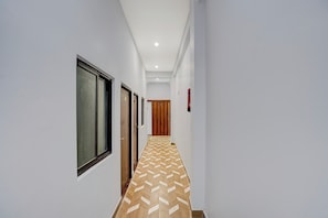 Un couloir avec un sol à motifs, des portes et un extincteur.