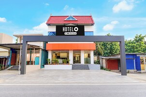 Et hotel med et tydeligt skilt, rødt tag og en moderne indgang.