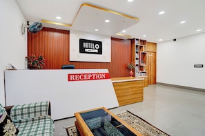 A hotel reception area with a reception desk, a reception sign, a conference area, and a reception chair.