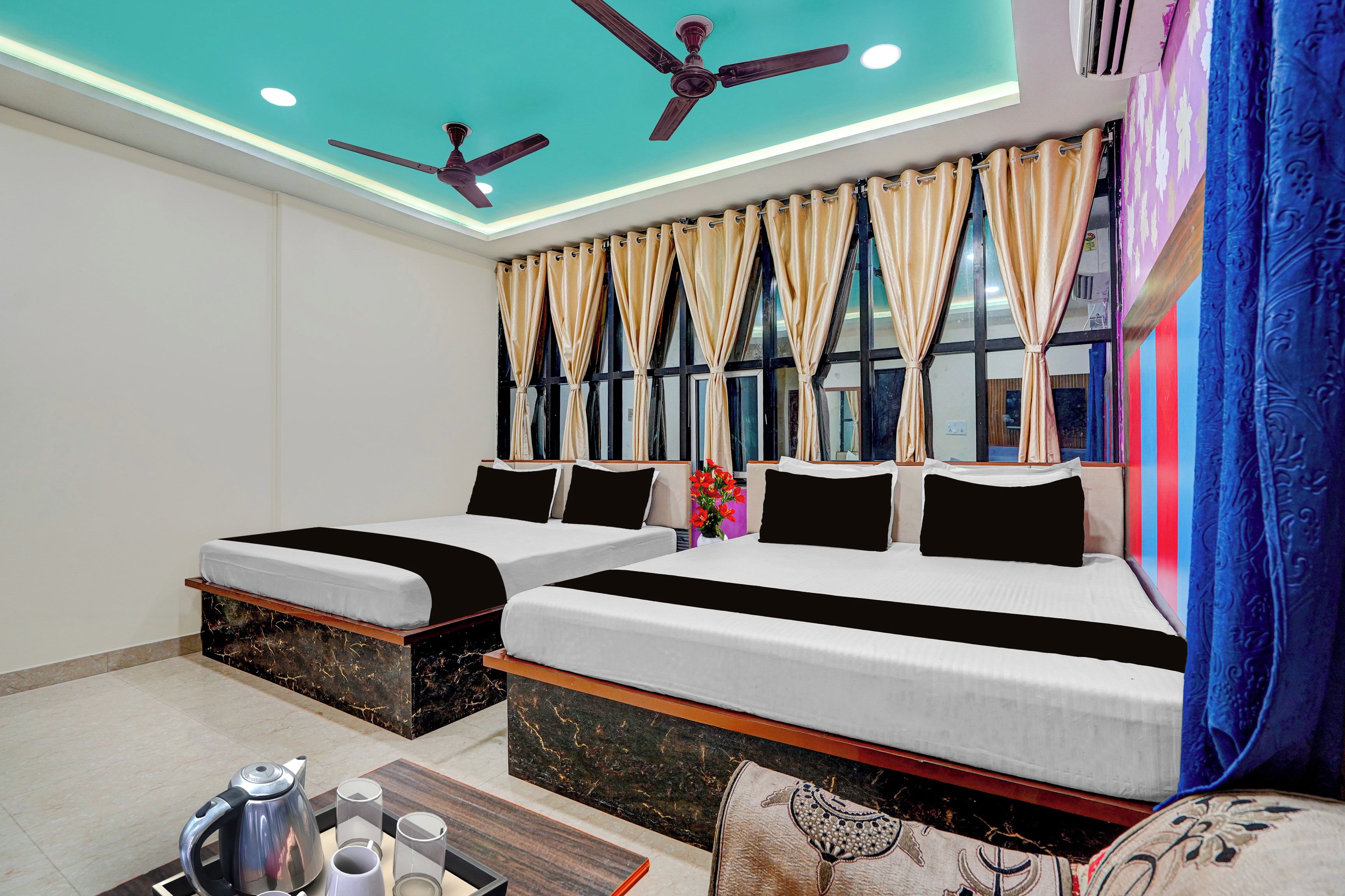 Habitación de hotel con dos camas, ventilador de techo y minibar.