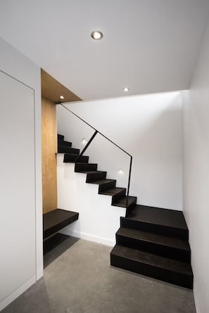 Una escalera moderna con un revestimiento de pared de madera e iluminación empotrada.