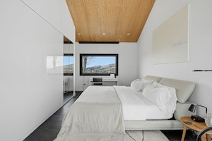 A modern bedroom with a large bed, a desk, and a view of the outdoors. - LE BOLTON - Exceptional architect-designed mountain chalet with a pool (Bolton-Est)