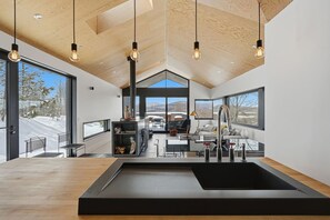 A modern kitchen with a central island, large windows, and a view of the outdoors. - LE BOLTON - Exceptional architect-designed mountain chalet with a pool (Bolton-Est)