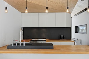 A modern kitchen with a wooden countertop, black backsplash, and pendant lighting. - LE BOLTON - Exceptional architect-designed mountain chalet with a pool (Bolton-Est)
