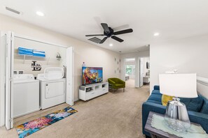 Ein modernes Wohnzimmer mit einer Couch, einem Fernseher und einem Deckenventilator.