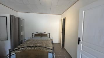 Een slaapkamer met een bed, een kledingkast, een deur en een betegelde vloer.
