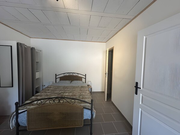 A bedroom with a bed, a wardrobe, a door, and a tiled floor. - Studio 'Le Bonheur Vosgien' with Mountain View, Wi-Fi and Parking (Ventron)