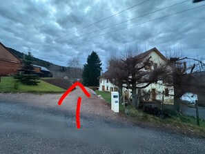 Camí rural amb una casa a la dreta i una granja a l'esquerra.