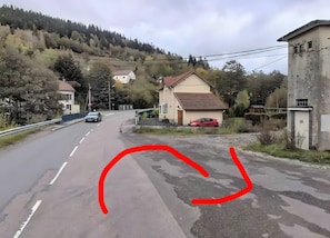 Une route avec une voiture qui roule, une maison et un immeuble dont la façade est endommagée.