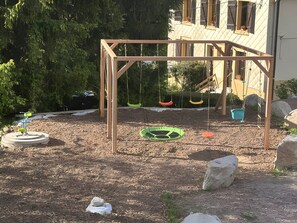 Une aire de jeux avec une balançoire en bois et une balançoire faite d’un pneu.