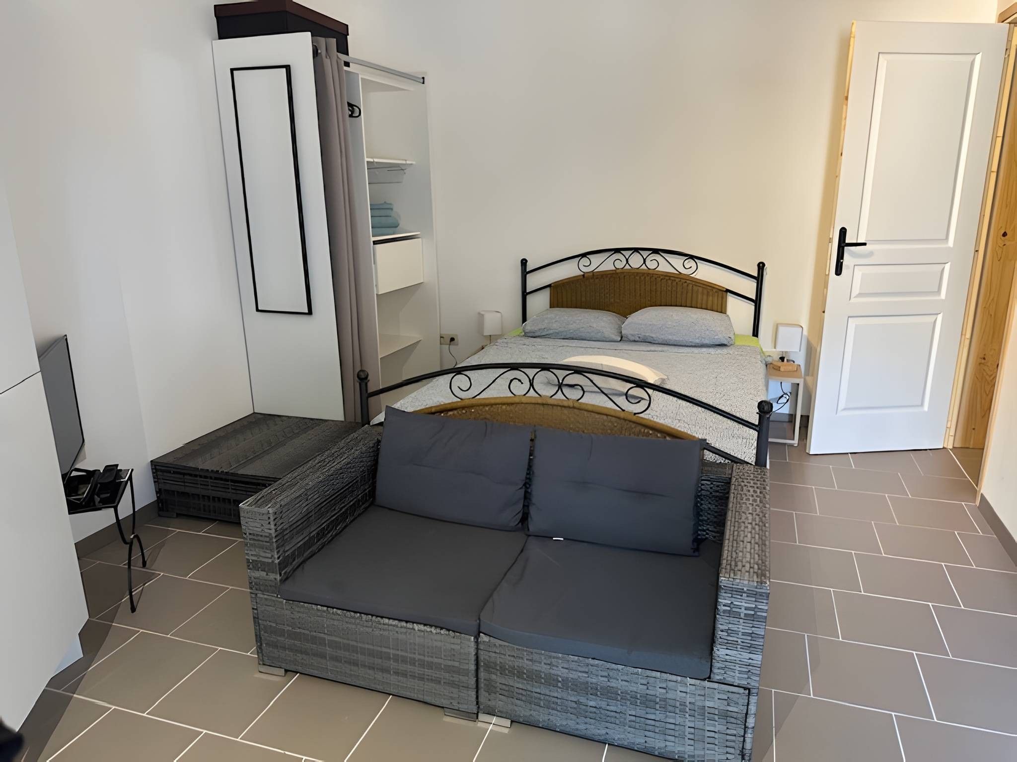Une chambre à coucher de taille réduite, comprenant un lit, un canapé et une armoire.