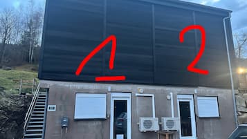 Un bâtiment avec une grande enseigne noire, deux portes et un appareil de climatisation.