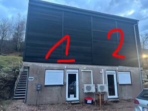 Un bâtiment avec une grande enseigne noire, deux portes et un appareil de climatisation.