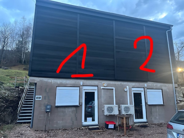 Un bâtiment avec une grande enseigne noire, deux portes et un appareil de climatisation.