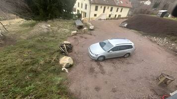 Une allée de gravier mène à une maison dotée d’un toit en pente et de nombreuses fenêtres.