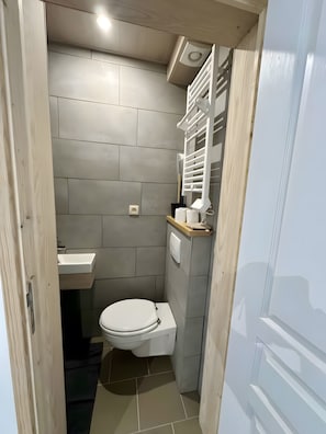 Une petite salle de bain comprenant des toilettes, un lavabo et un porte-serviettes.
