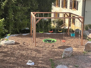 Une aire de jeux avec des balançoires et une structure d’escalade.