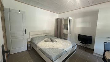 Une chambre à coucher avec un lit, une télévision, une armoire et une porte.