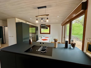 Una cucina moderna con isola centrale, elettrodomestici integrati e ampie finestre con vista sull'esterno.