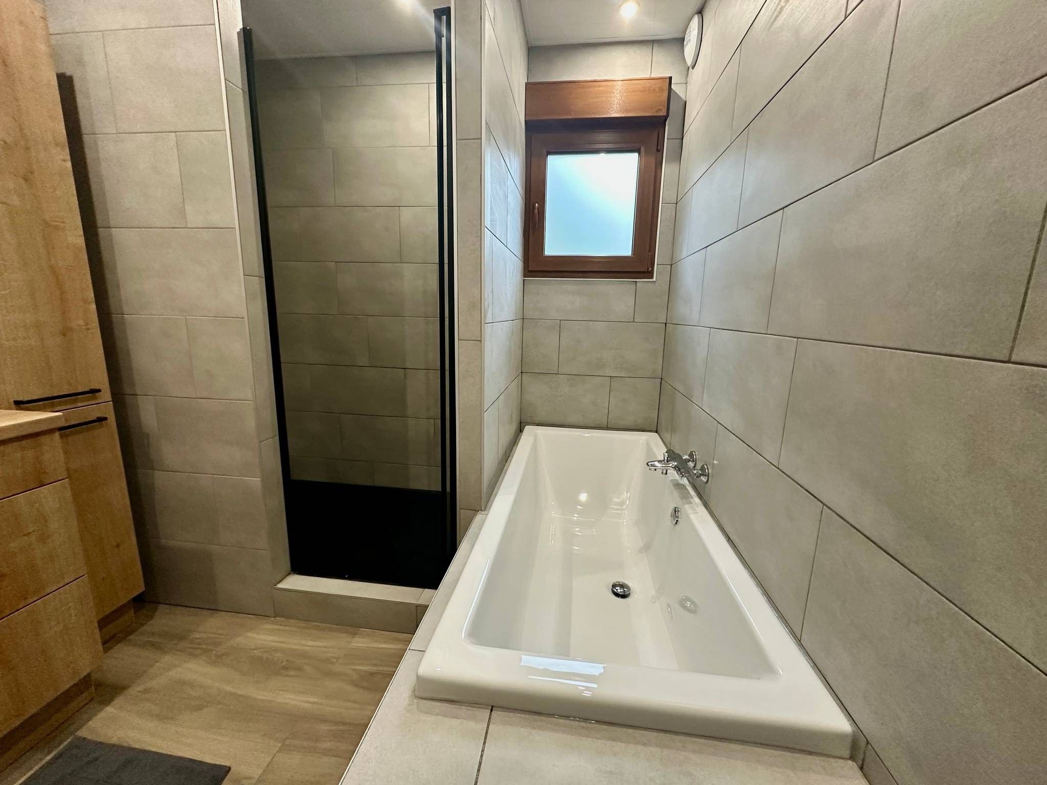 Une salle de bain moderne avec une douche à l’italienne, une baignoire sur pieds et un meuble en bois.