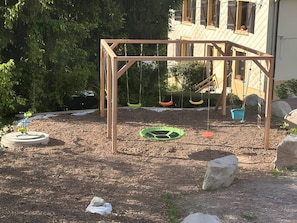 Un'area giochi con altalene di legno e un’altalena a pneumatico.