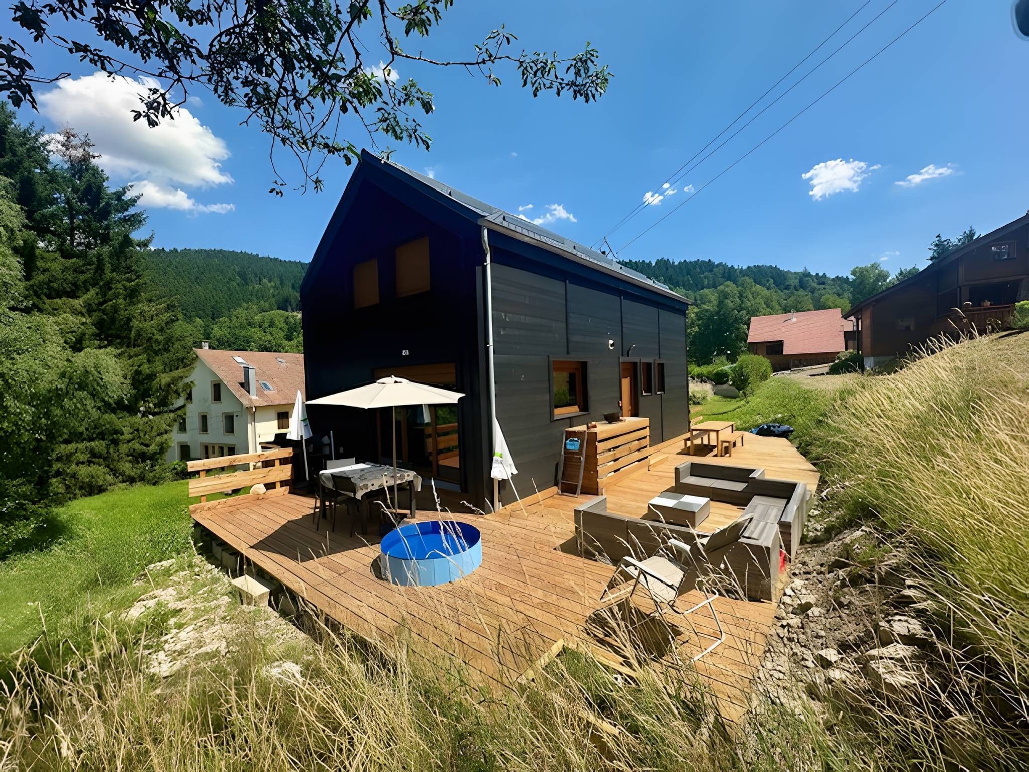 Une maison moderne dotée d’une terrasse en bois, d’un espace salon extérieur et d’une piscine.