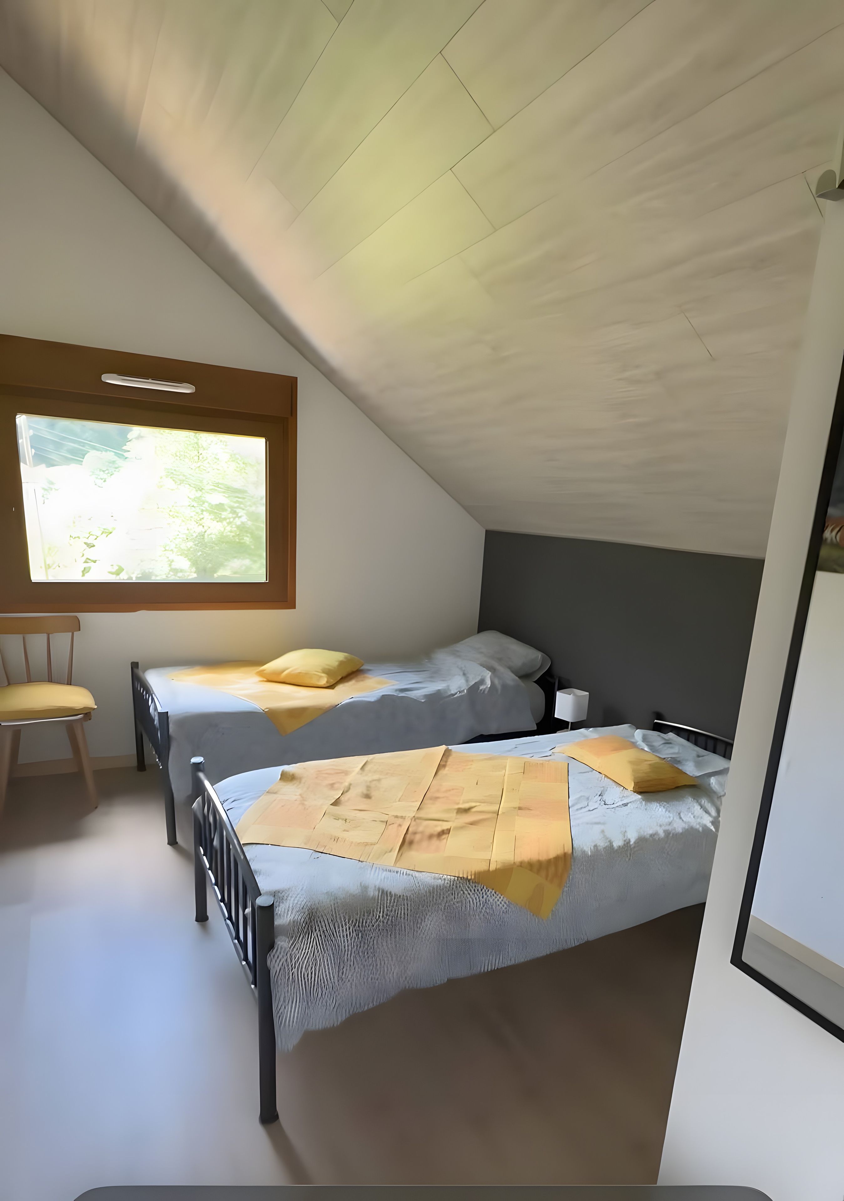 A bedroom with two beds, a window, and a chair.