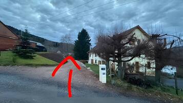 A rural road with a house on the right and a barn on the left.