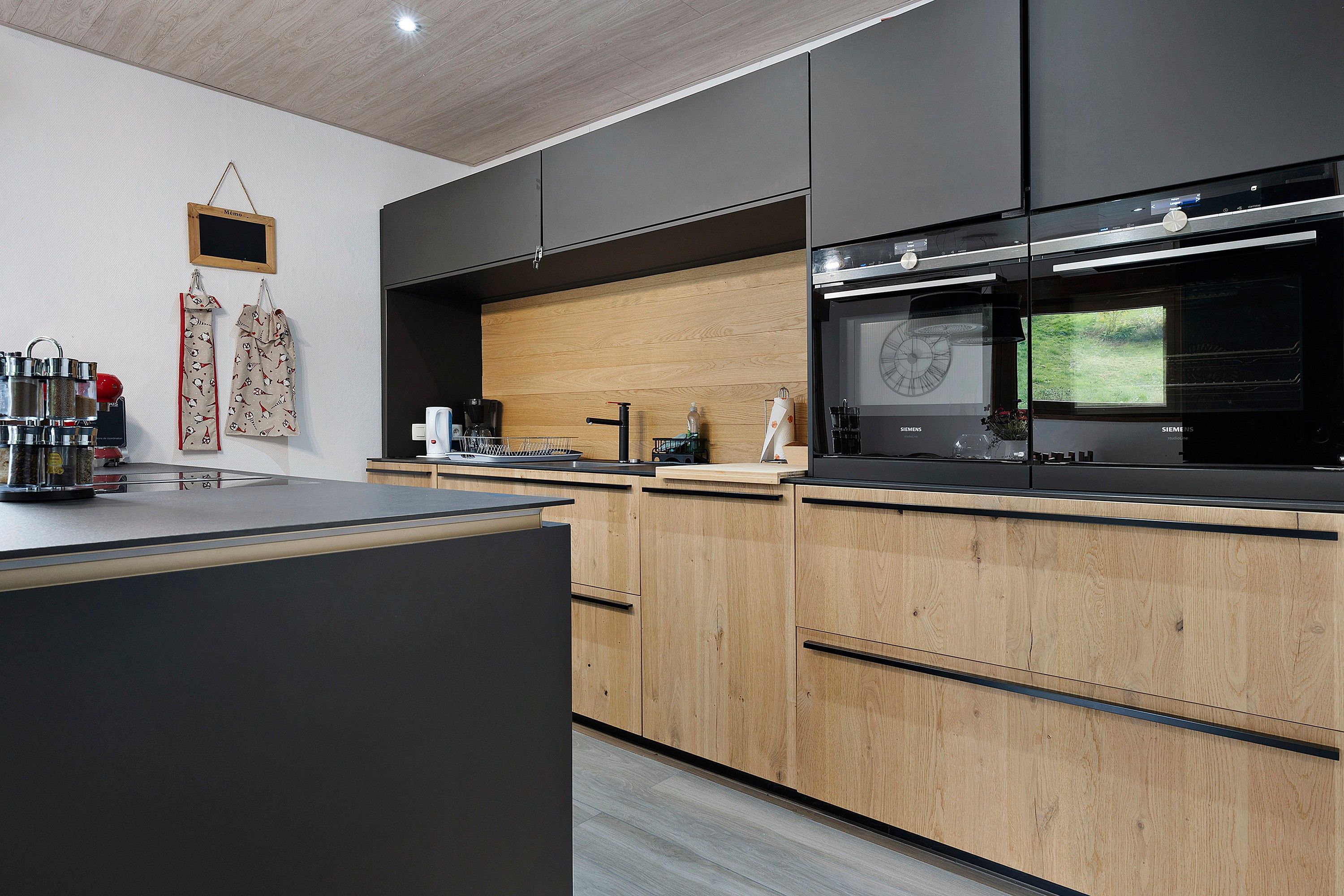 A modern kitchen with black cabinets, a wooden countertop, and a built-in oven.